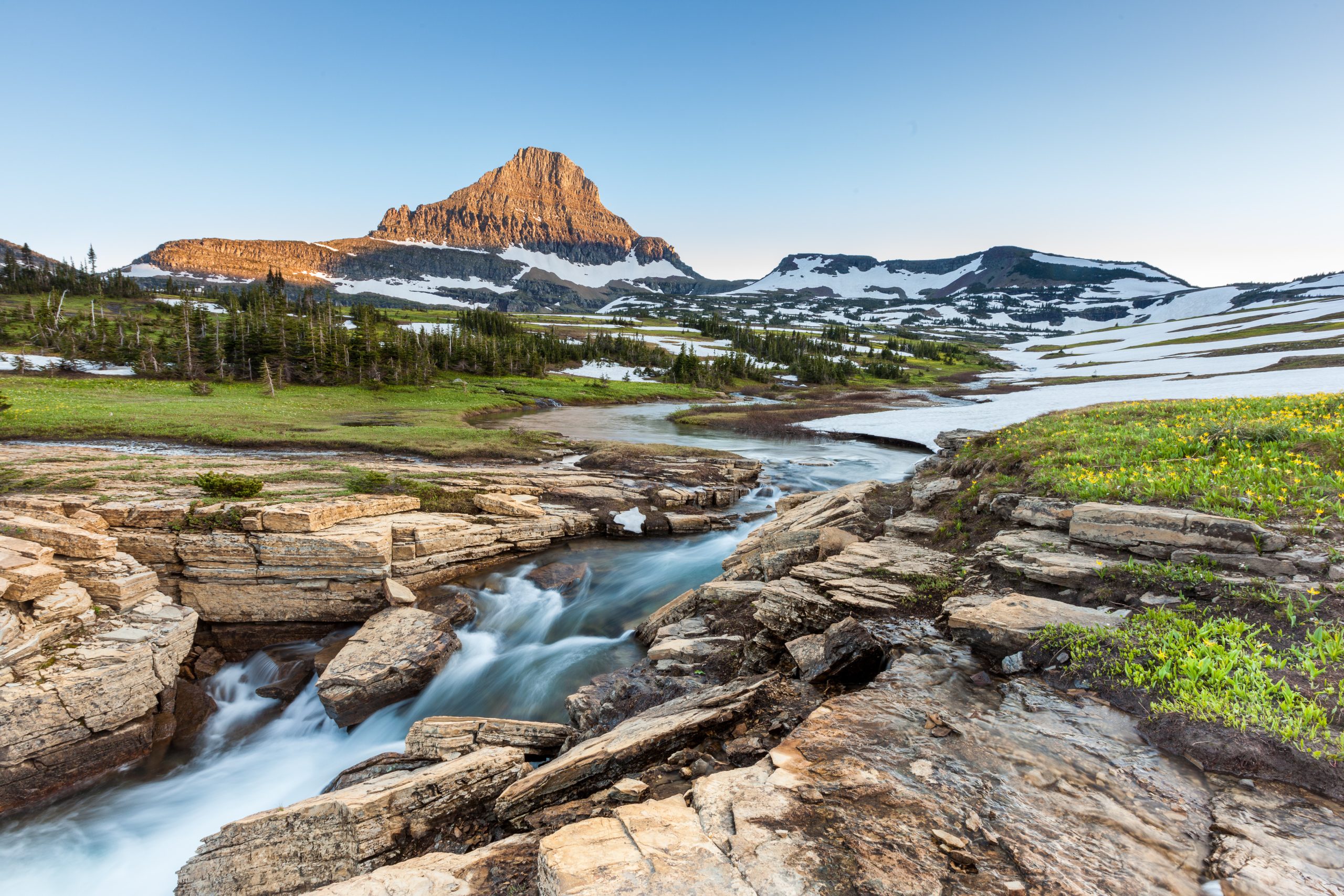 Waterfall at Logan Pass in Glacier National Park Montana with Reynolds Mountain in the background covered in snow